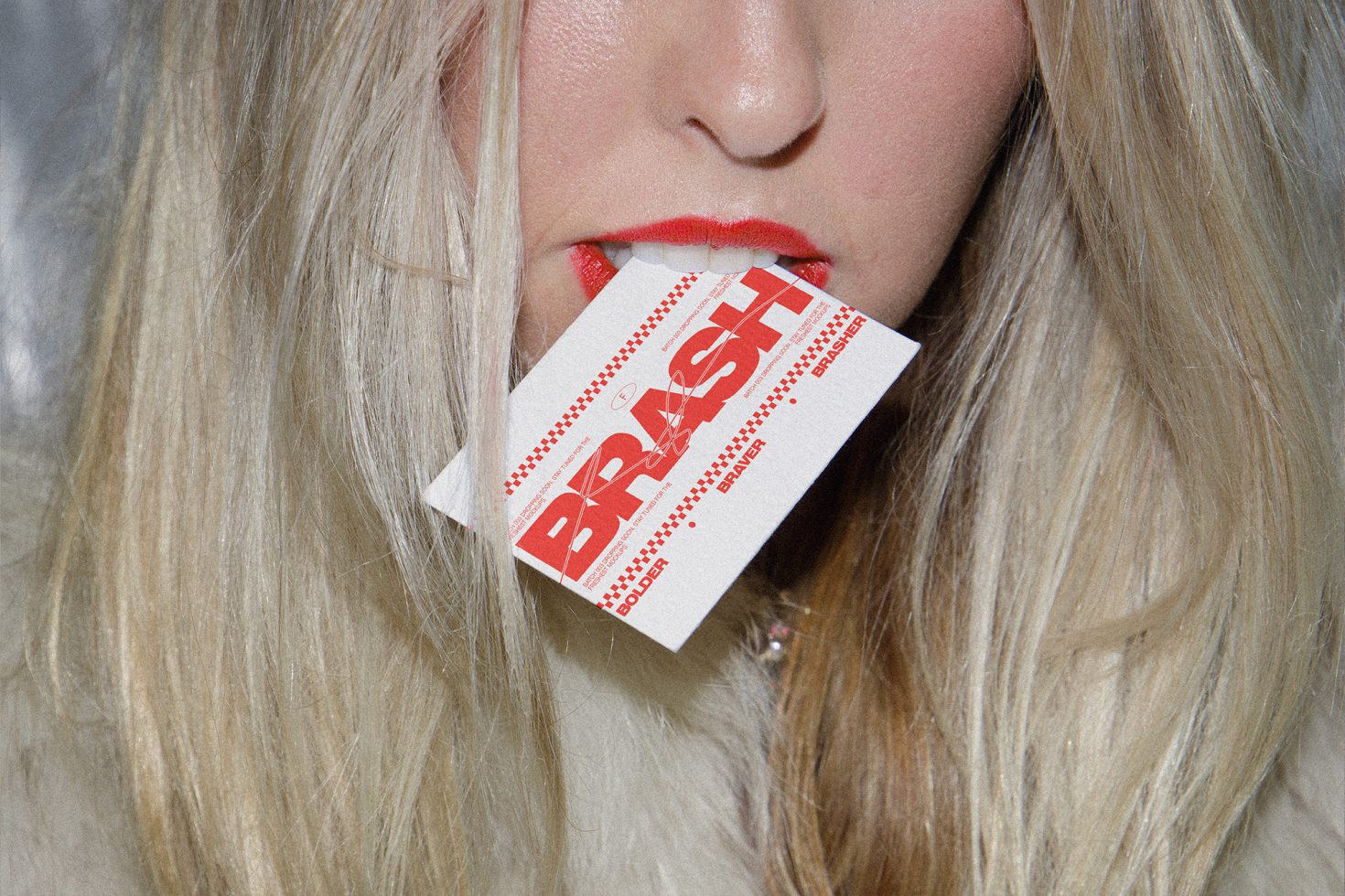 Close-up of a woman holding a typography card with "BRASH" between her lips, showcasing bold red font design, mockup for graphic designers.